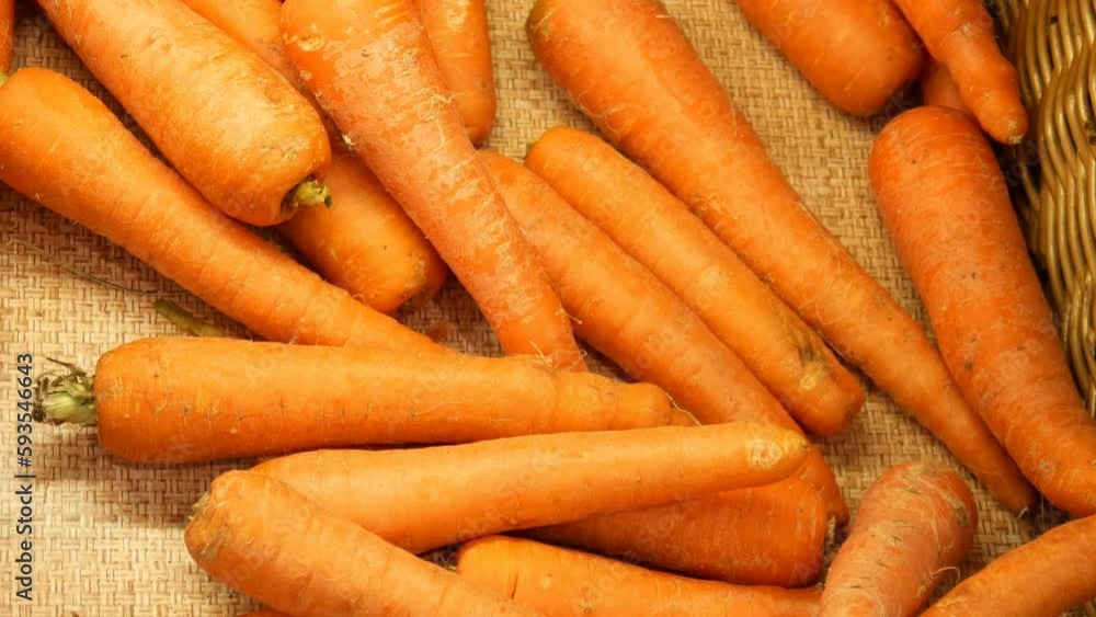 Close-up of many carrots in a wicker basket and male hands take a few Close-up of many carrots in a wicker basket and male hands take a few