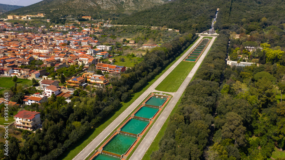 Aerial view of the fountains in the Royal Palace of Caserta also known as Reggia di Caserta. It is a former royal residence in Caserta, near Naples, Italy. In the background the Grand Cascade and city Aerial view of the fountains in the Royal Palace of Caserta also known as Reggia di Caserta. It is a former royal residence in Caserta, near Naples, Italy. In the background the Grand Cascade and city