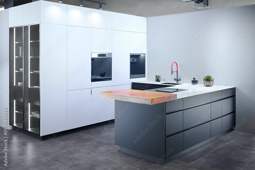 Upscale modern flat design loft kitchen with Induction cooker black glass hob with integrated hood or aspirating induction hob on marble light stoneware countertop panels with flower in vase and sink. Upscale modern flat design loft kitchen with Induction cooker black glass hob with integrated hood or aspirating induction hob on marble light stoneware countertop panels with flower in vase and sink.