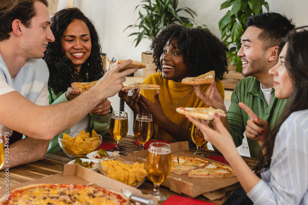 Happy multiracial friends eating pizza together at home - happy friends meal , food delivery young people having dinner indoors.