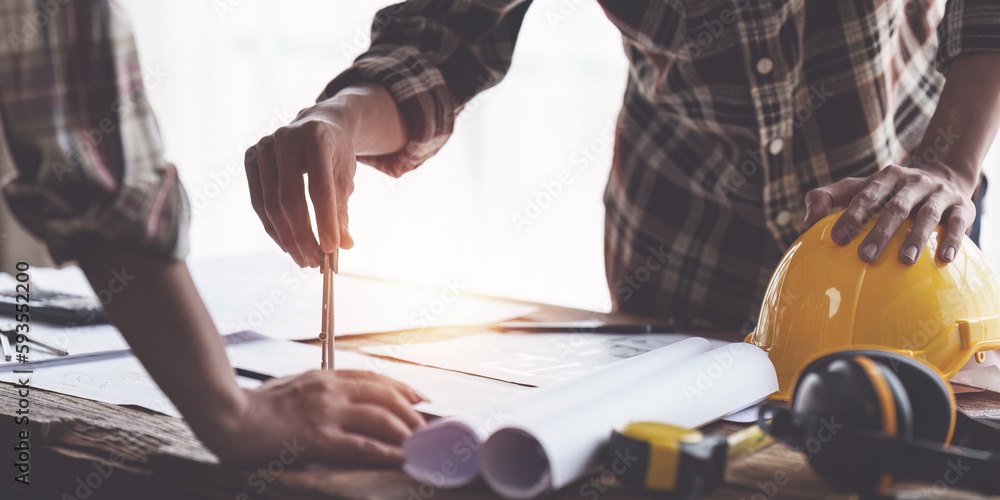 Obraz premium Architect and Engineer working with blueprints for architectural plan, engineer sketching a construction project, green energy concept