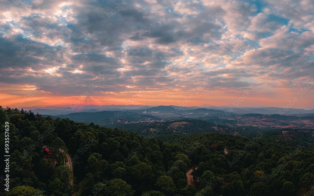 Drone shot of a mountain road going through a green dense forest at sunset in Mazamitla Town, Mexico