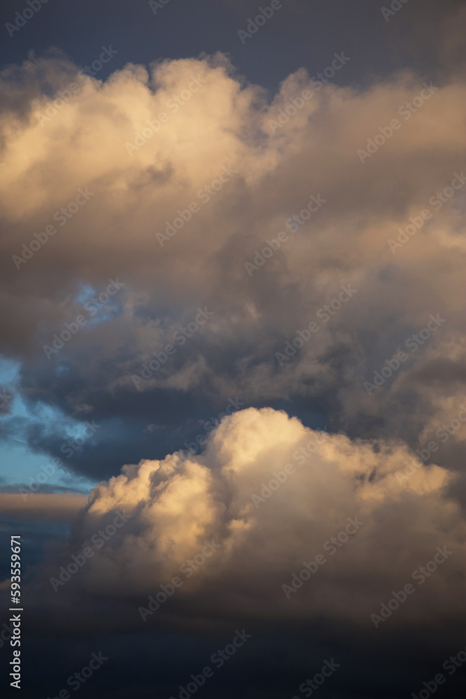 Storm cloudy dramatic sky with dark rain grey cumulus cloud in yellow sunlight and blue sky background texture, thunderstorm, heaven