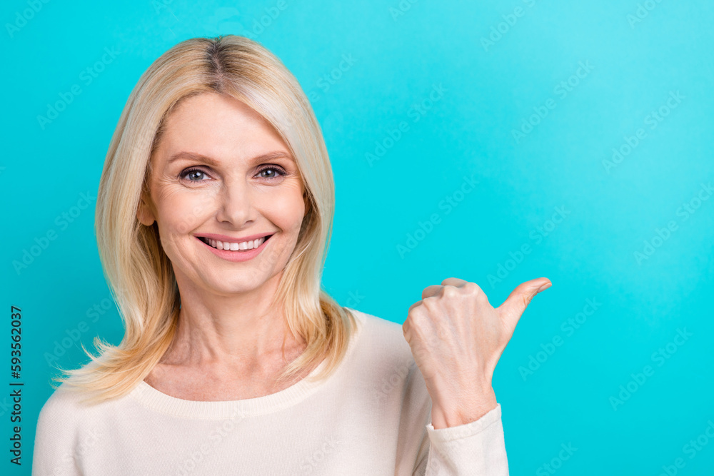 Fototapeta premium Photo of charming cute woman wear white shirt pointing thumb empty space isolated turquoise color background