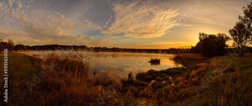 panorama sunrise over pond with mist and reeds
