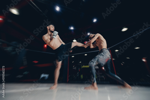 Two man MMA boxers fighters in fights without rules in ring octagon, dark background, motion blur