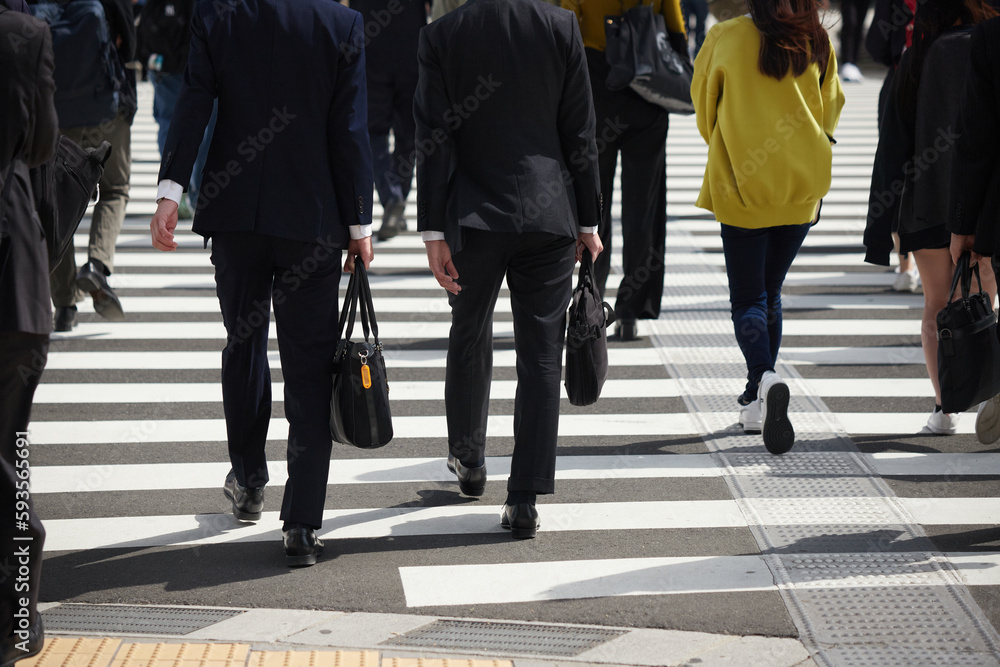 都市の交差点の横断歩道を渡るビジネスマンと人々の姿