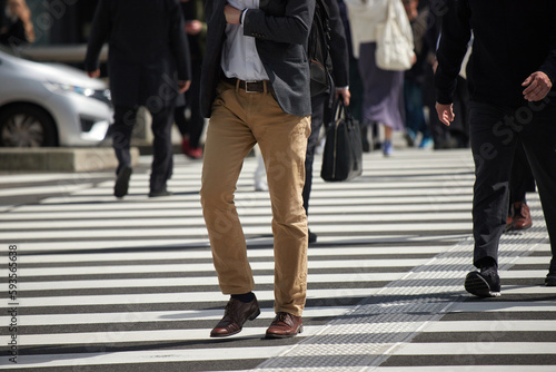 都市の交差点の横断歩道を渡るビジネスマンと人々の姿