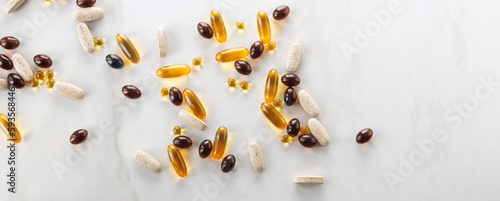various capsules with vitamins and supplements on a light table, space for text