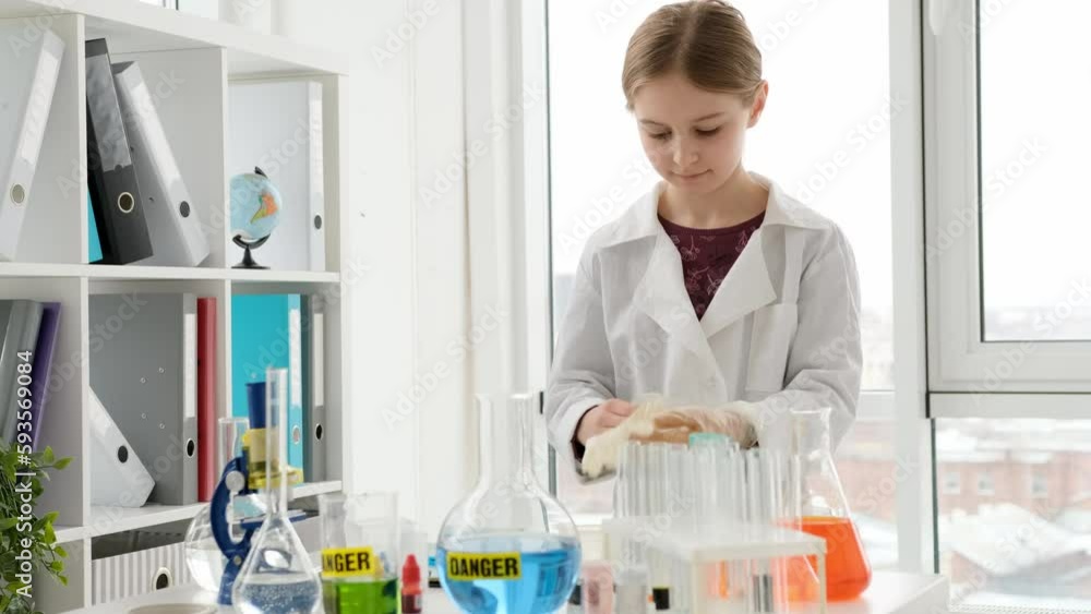 School girl wearing medical gloves in chemistry class. Female pupil studying in lab School girl wearing medical gloves in chemistry class. Female pupil studying in lab