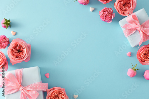 Top view photo of natural flowers pink peony rose buds gift boxes and small hearts baubles on isolated light blue background with empty space in the middle. Mother Day concept