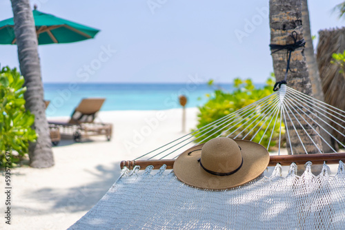 Fototapeta Naklejka Na Ścianę i Meble -  A straw hat lying on the hammock in the background of the landscape of the Maldives. Travel and tropical vacation concept