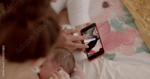 Young parents look at photos on the phone. On the screen is a portrait of two women with a positive pregnancy test. 17.09.2022 Konevova, Prague, CZ photo