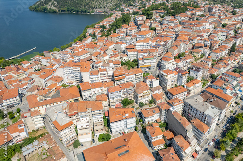 Aerial view of traditional village with rural houses, white buildings with orange roofs in the middle of lake. Greece. Drone, copter view