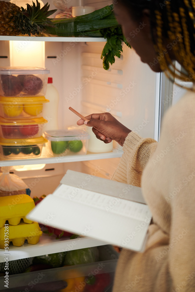 Woman opening fridge and writing down shopping list Woman opening fridge and writing down shopping list