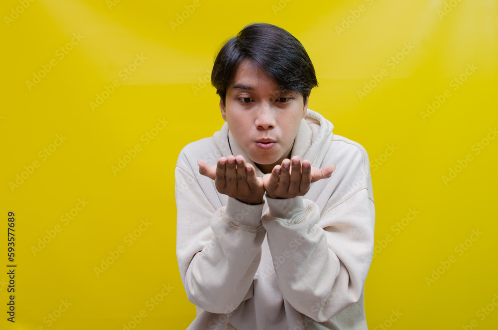 For advertising and product placement concepts, a happy, smiling young Asian man opens his palm and points to copy space. For advertising and product placement concepts, a happy, smiling young Asian man opens his palm and points to copy space.