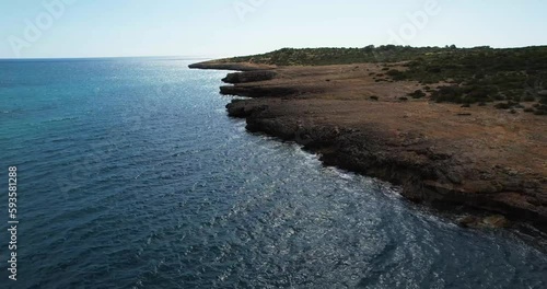 Aerial shot flying over a low cliff and revealing the rugged coastline of Mallorca