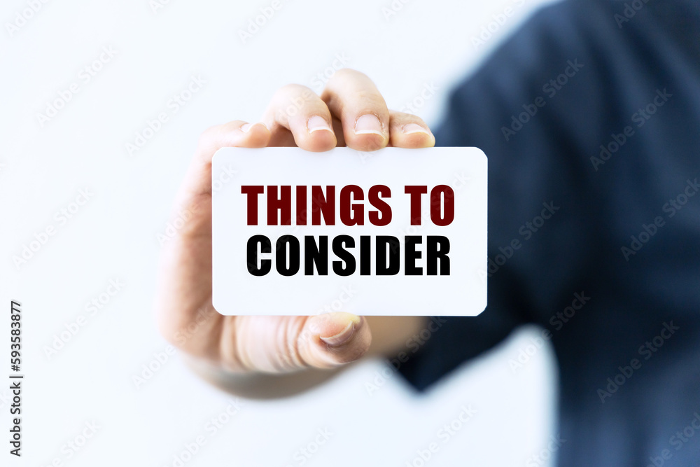Things to consider text on blank business card being held by a woman's hand with blurred background. Business concept about things to consider. Things to consider text on blank business card being held by a woman's hand with blurred background. Business concept about things to consider.