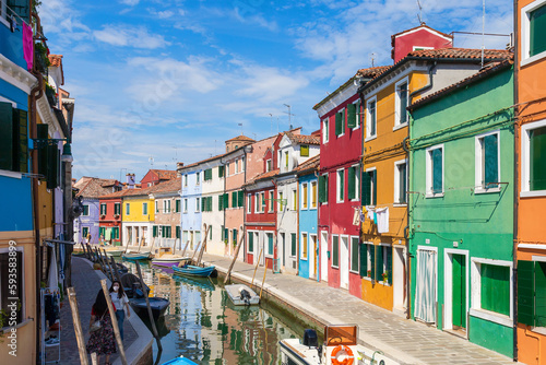 Multicolored colorful houses in Venice on the island of Burano. Narrow canal with motor boats along the houses. Summer sunny day. Selective focus. © tasha_lyubina