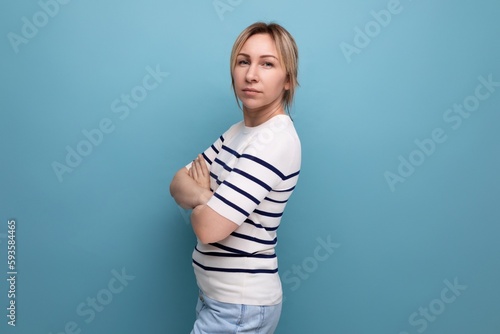 serious sullen blond girl clasped her hands together on a blue background with copyspace