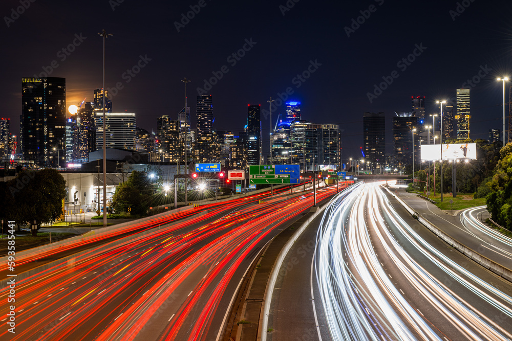 Fototapeta premium Cars travel on the Westgate Freeway at night in front of the Melbourne City Skyline