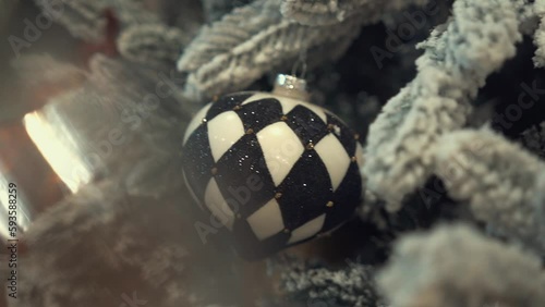 Christmas tree decorated with artificial snow, shining lights, golden feathers, multicolor Christmas tree toys and balls with glitter. Winter holidays with family and presents in a cozy home. 