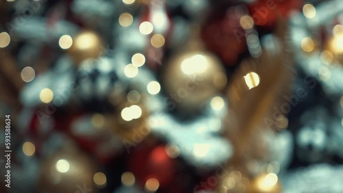 Christmas tree decorated with artificial snow, shining lights, golden feathers, multicolor Christmas tree toys and balls with glitter. Winter holidays with family and presents in a cozy home. 
