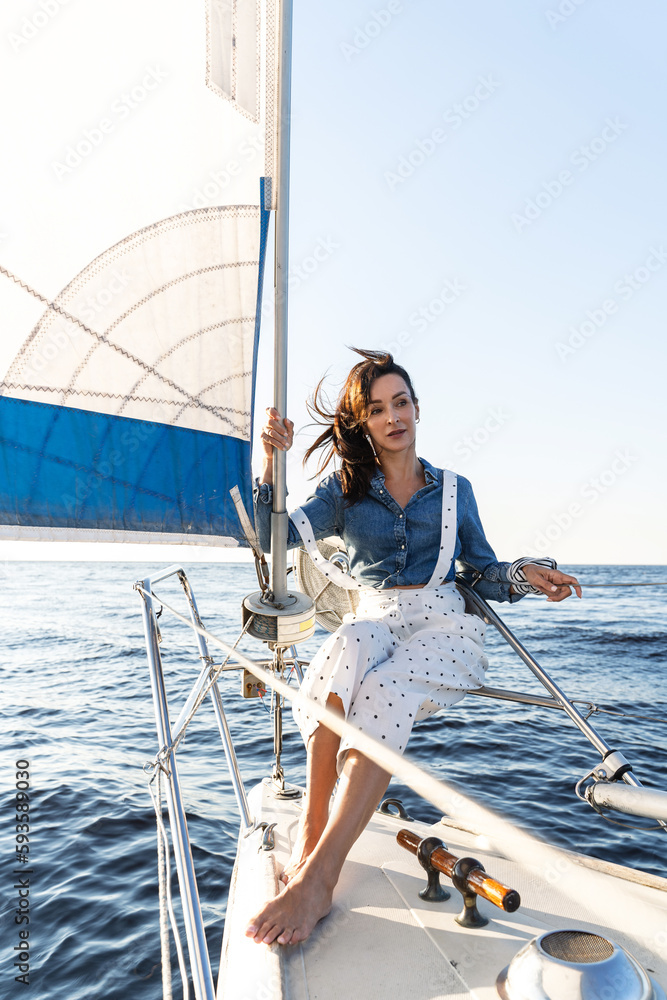 Attractive woman relaxing on sailboat during sailing in sea Attractive woman relaxing on sailboat during sailing in sea