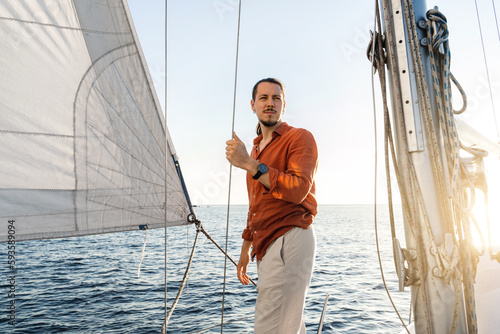 Young handsome man during on his sailboat during sailing in sea