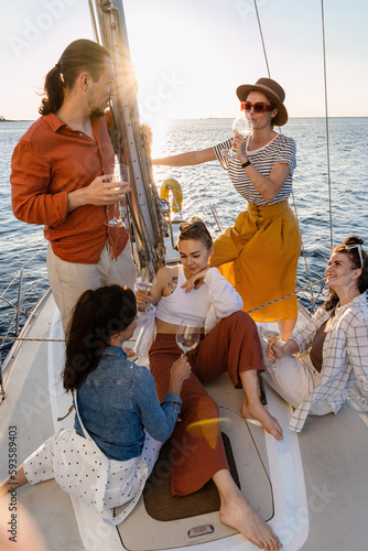 Group of happy friends drinking wine and relaxing on the sailboat during sailing in sea © blackday