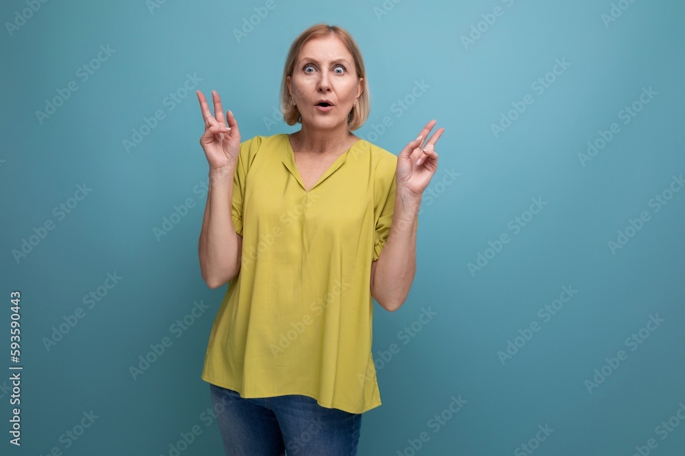thoughtful blonde mature woman in yellow t-shirt with emotions of surprise thoughtful blonde mature woman in yellow t-shirt with emotions of surprise