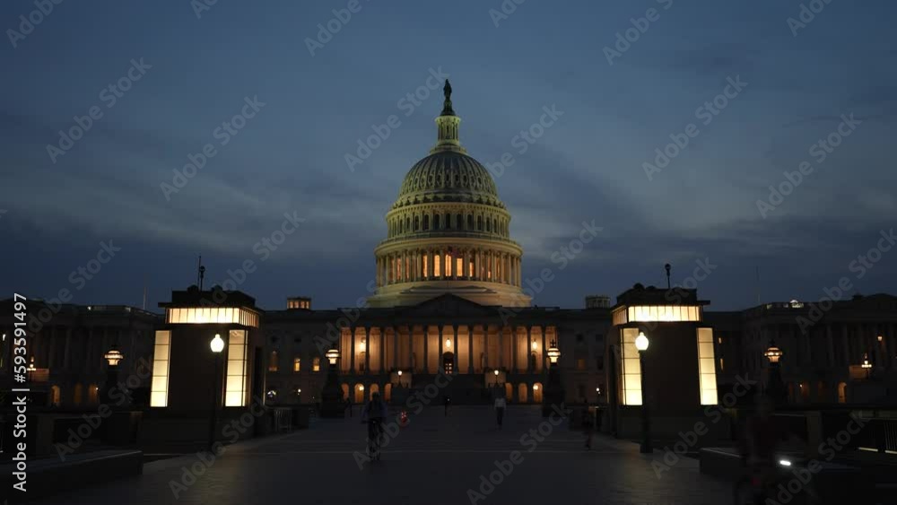 Push in to the US Capitol with lights and flags waving in Washington DC at night set against a night blue purple sky. Push in to the US Capitol with lights and flags waving in Washington DC at night set against a night blue purple sky.