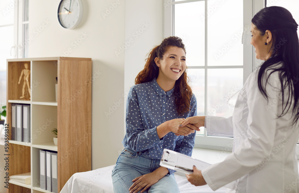 Smiling doctor and patient exchange handshakes. Cheerful beautiful