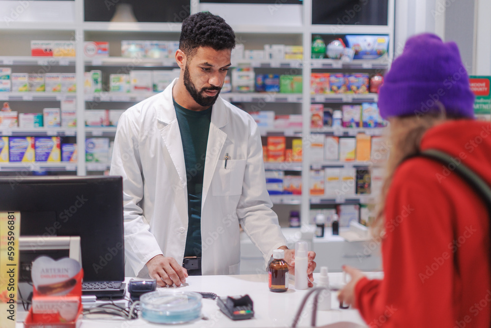 Fototapeta premium Multiracial pharmacist selling medications to young woman.