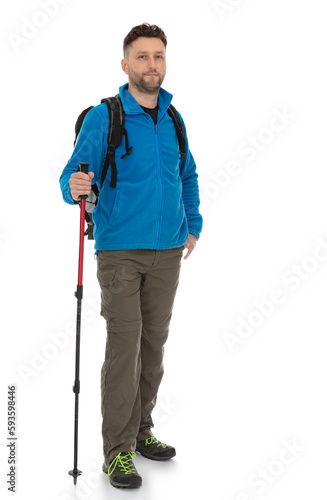 Full-length portrait of trekker with a backpack isolated on white background. Thirty years old man in blue jacket standing with trekking pole, posing in studio.