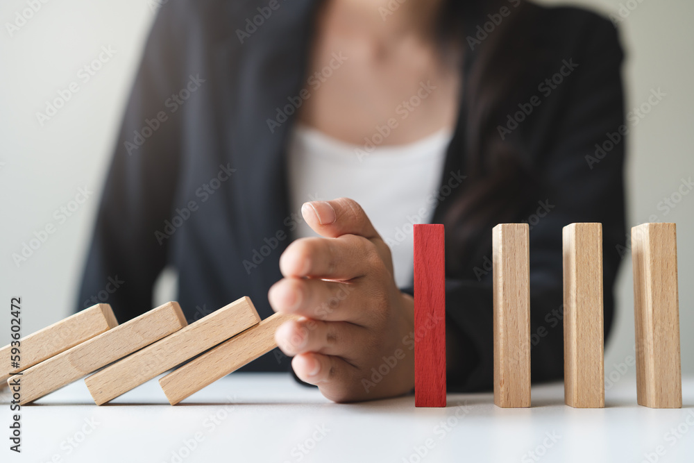 Risk management to Protection finance from domino effect concept. Hands stop domino effect before complete fall.