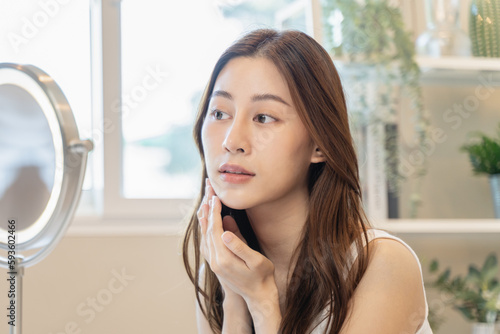 Close up young beautiful asian woman looking at mirror at home