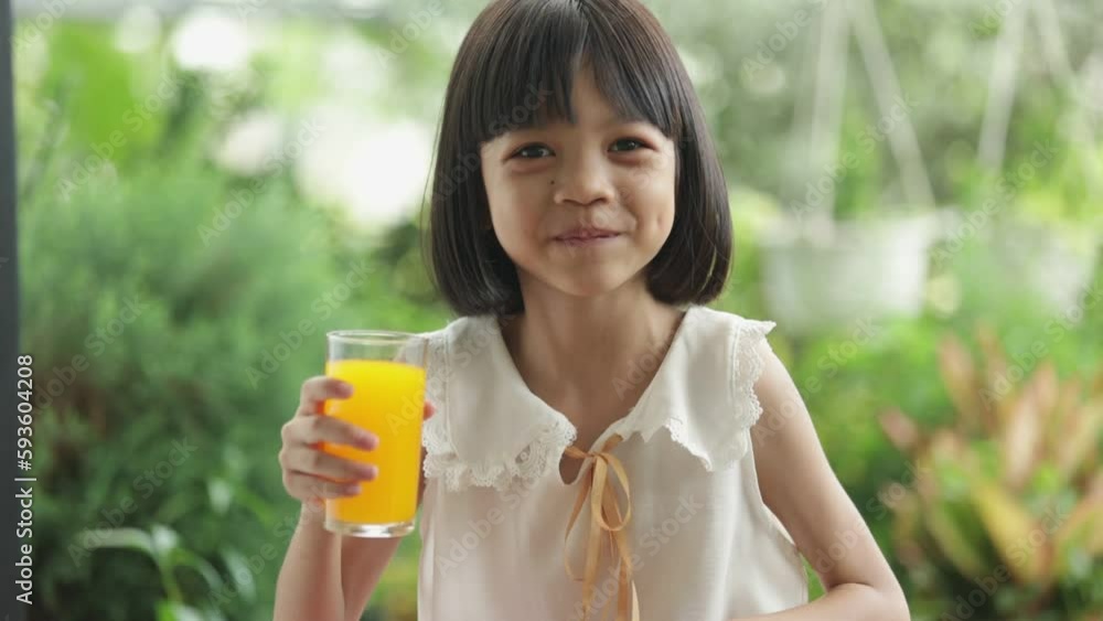An Asian girl, cute face, smiling face. she was holding a glass of orange juice in her hand and drinking it delicious and refreshing her body. In the shady green backyard. with different pose. An Asian girl, cute face, smiling face. she was holding a glass of orange juice in her hand and drinking it delicious and refreshing her body. In the shady green backyard. with different pose.