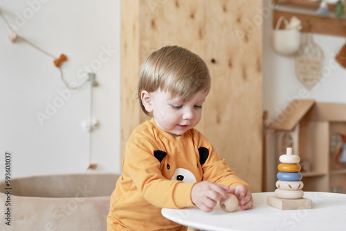 Baby child plays with wooden toys pyramid. Early development