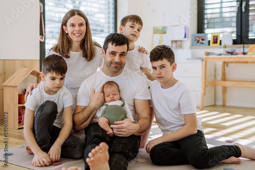 Portrait of big family with four kids enjoying their newborn baby.