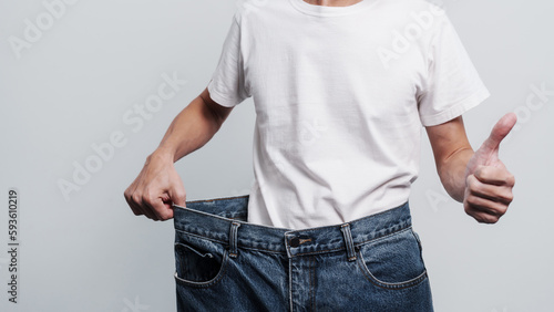 Fotografie Young confident asian chinese weight loss man with oversize of jean pants