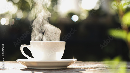 Extreme close-up natural steam smoke of coffee from hot coffee cup on old wooden table in morning warm sunlight flare, outdoor background. Concept hot drink, Coffee Cup, Mug, espresso, breakfast