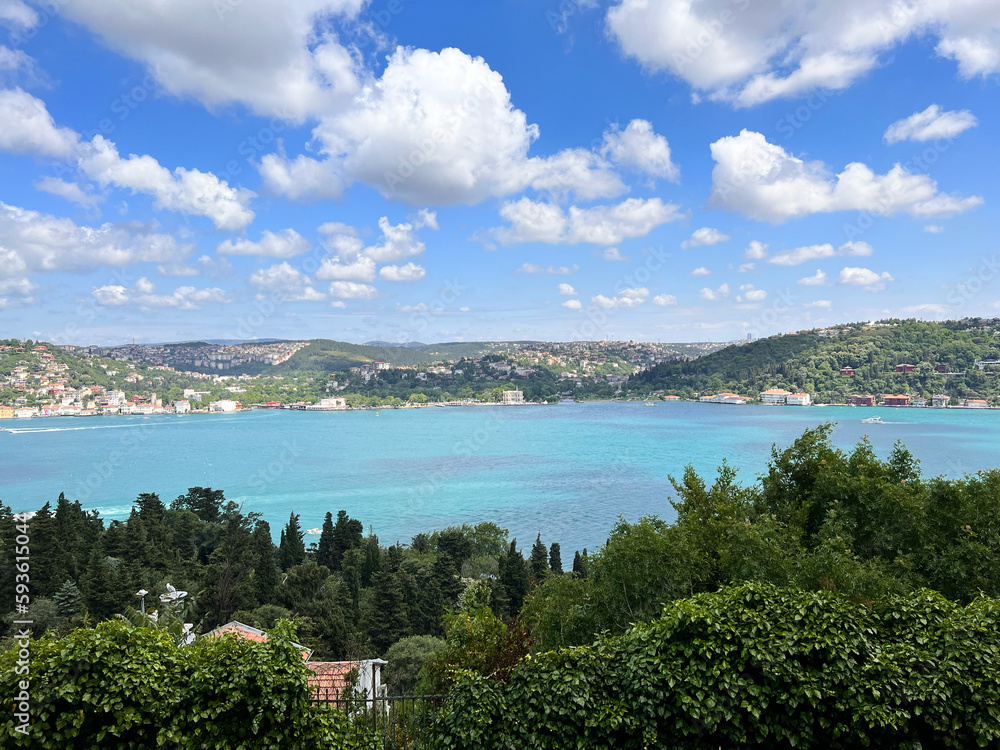 A gorgeous Bosphorus panorama taken from Aşiyan Hill, highlighting a spring atmosphere, azure sky with white clouds, turquoise sea, and thriving green trees, fusing city and nature. Bosphorus view.
