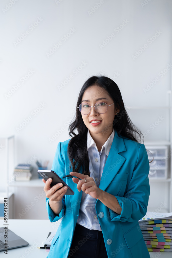 Beautiful Asian businesswoman using her smartphone, texting or chatting with her friends. Beautiful Asian businesswoman using her smartphone, texting or chatting with her friends.