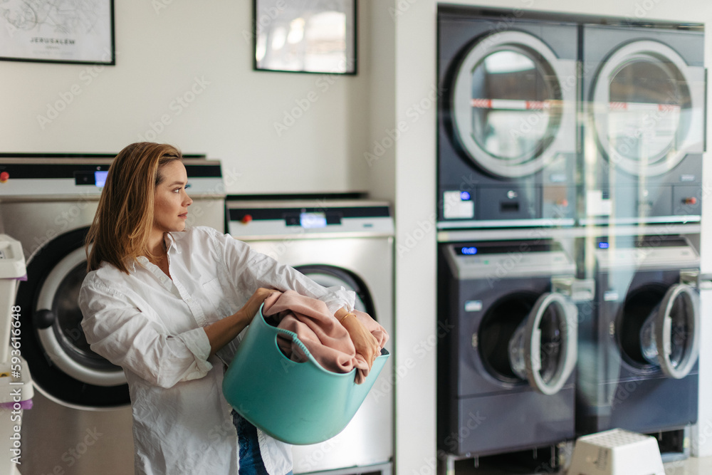 Young woman waiting in a laundry room. Young woman waiting in a laundry room.