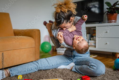 One young woman a mother playing at home on the floor with her one year old child, family playtime, early child development concept