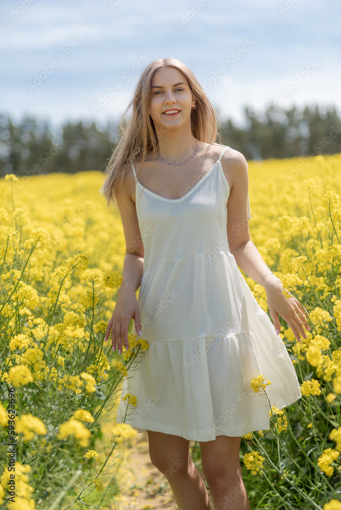 Beautiful woman with long blonde hair. He walks in the rapeseed field Beautiful woman with long blonde hair. He walks in the rapeseed field