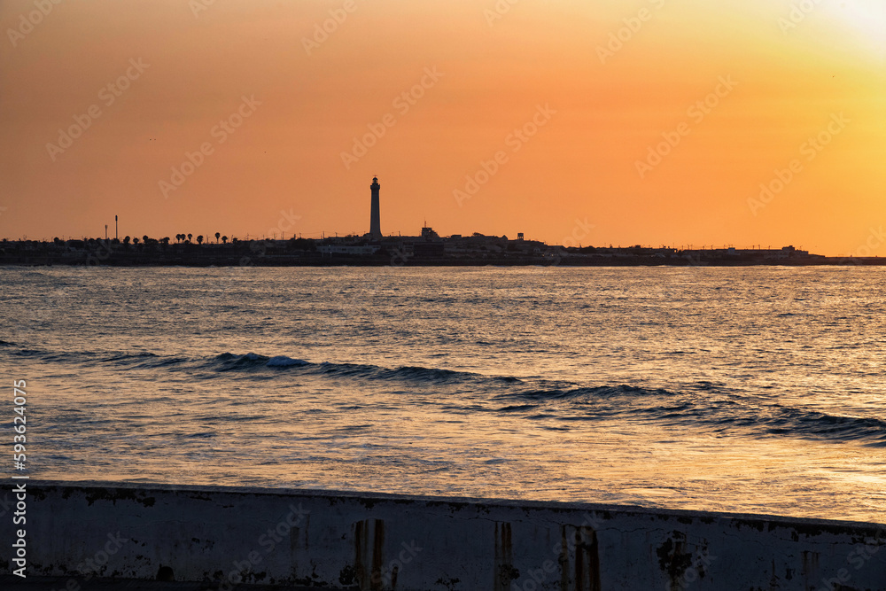 Sunset over the Atlantic Ocean in Casablanca. Morocco. With lighthouse on the background.