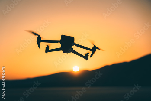 Silhouette of a quadcopter drone flying over the Mediterranean Sea during sunset in Crete, Greece