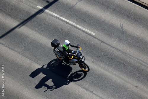 Motocyklista jedzie drogą asfaltową w mieście. Wyprzedzanie.